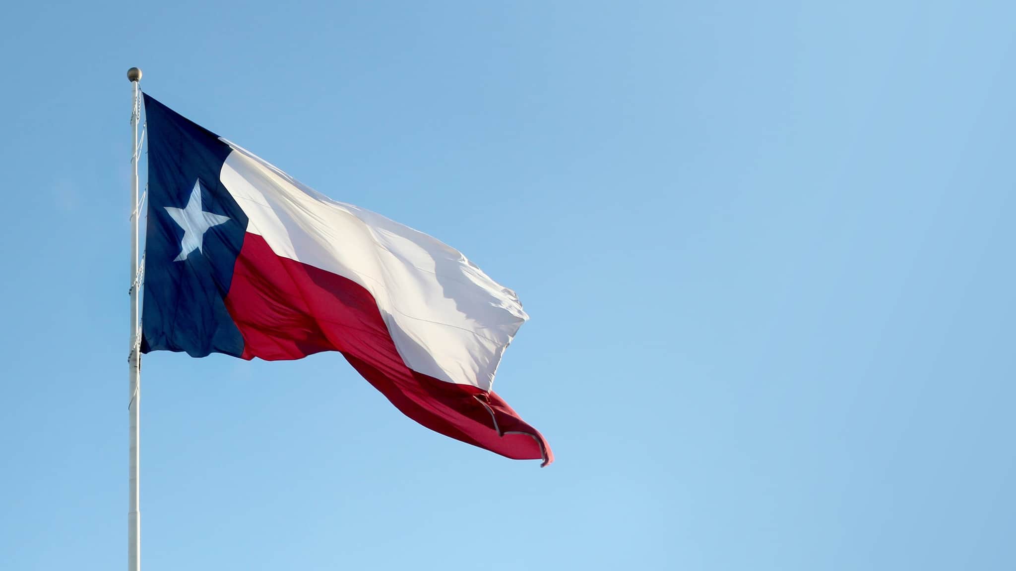 The Lone Star flag of Texas flying against a clear blue sky.