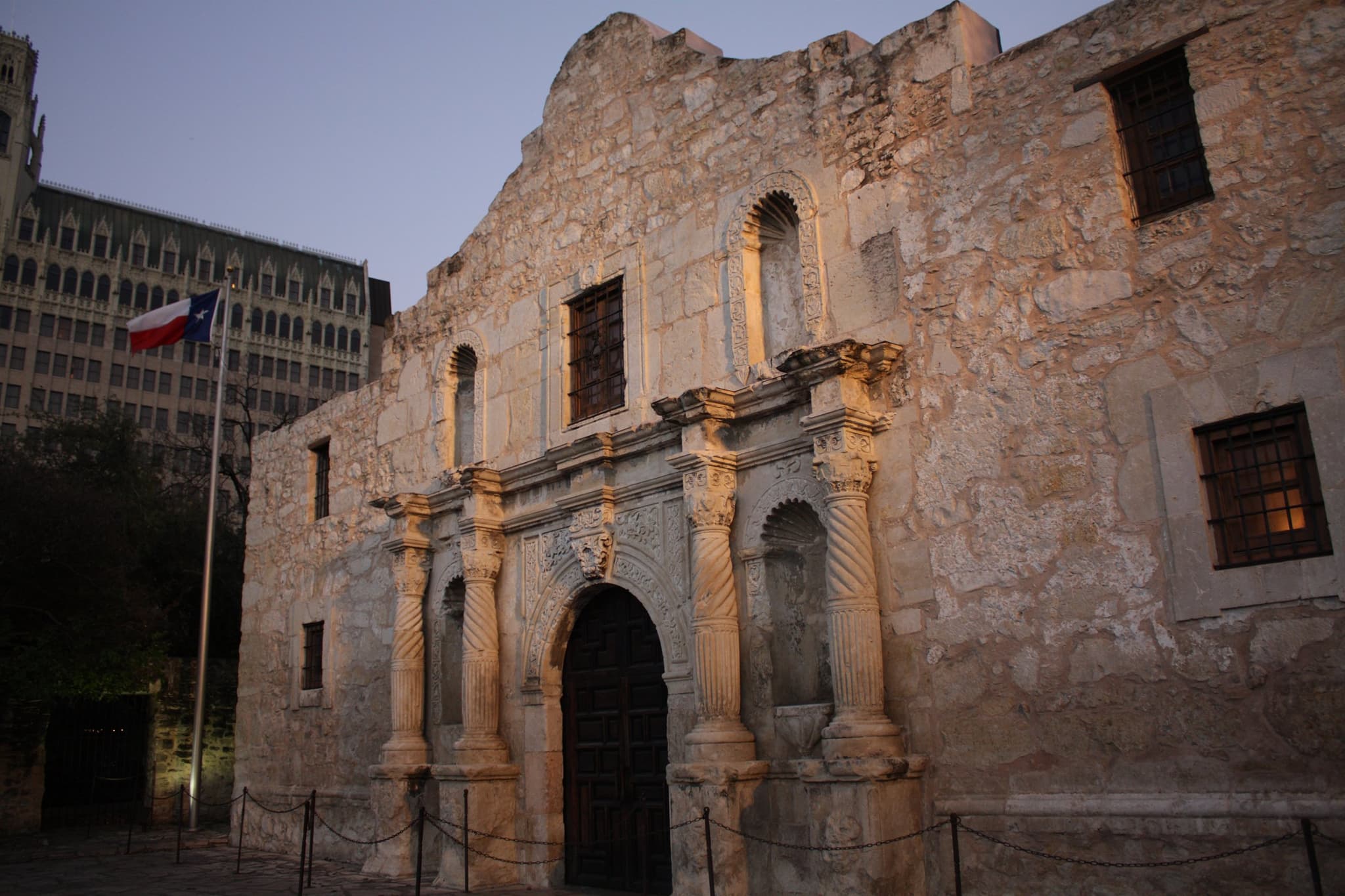 The Alamo at dusk, the Texas flag flying.