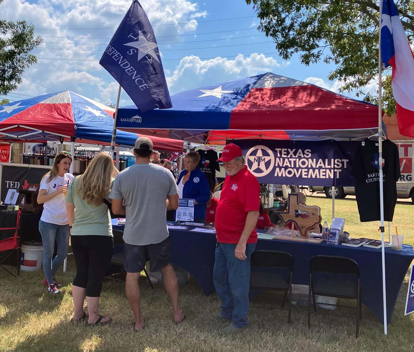 A Texas Nationalist Movement booth at a county fair, under Texas and independence flags.