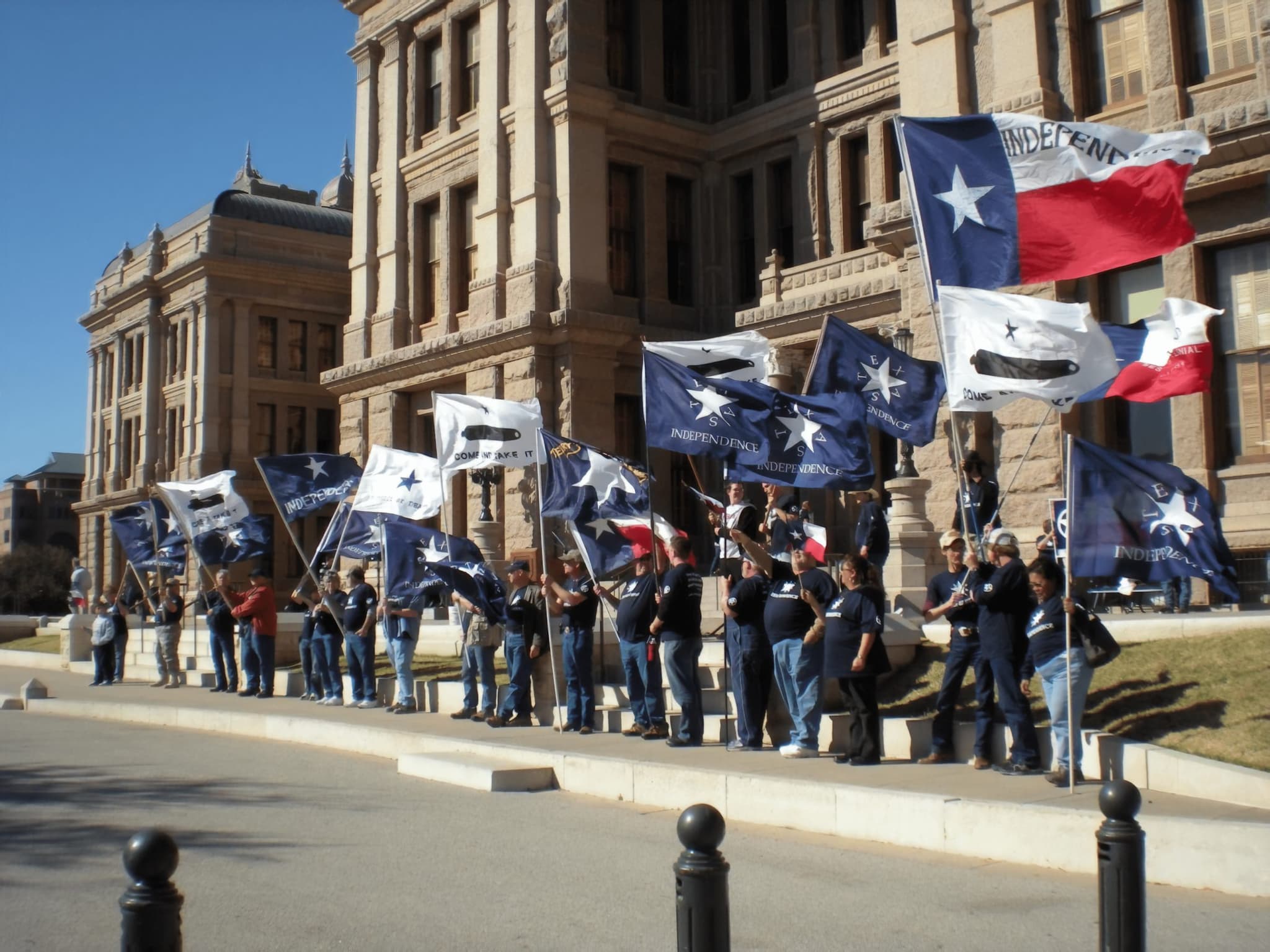 Texas Nationalist Movement members rallying at the Texas Capitol with Texas Independence flags.