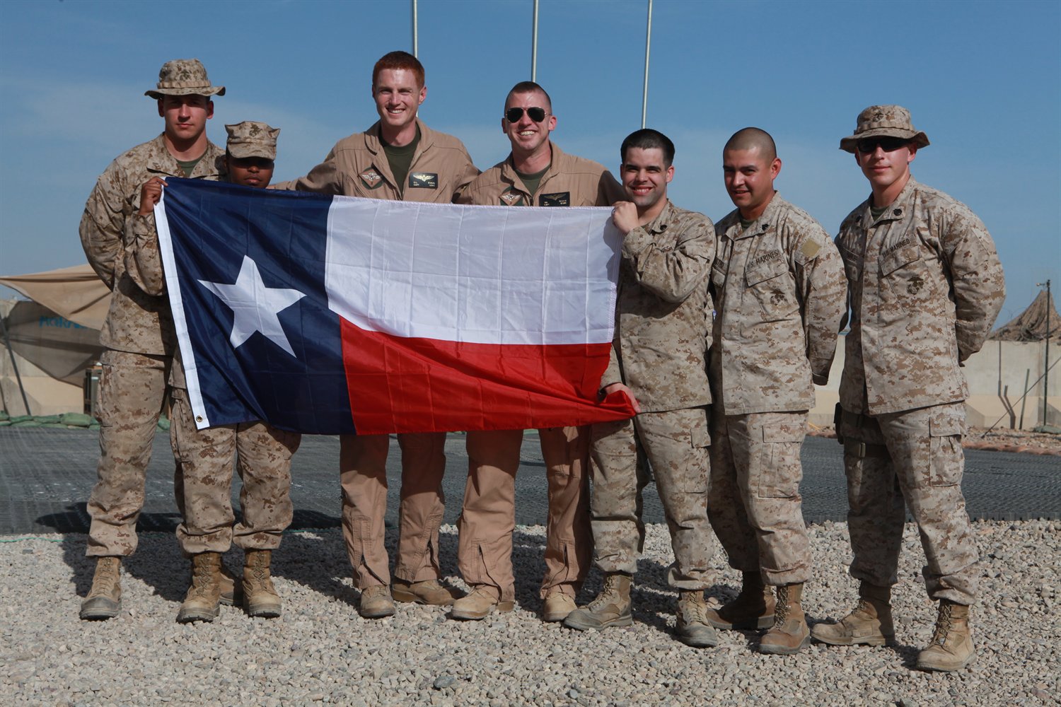 Texans serving in the U.S. Marine Corps hold up the Texas flag.